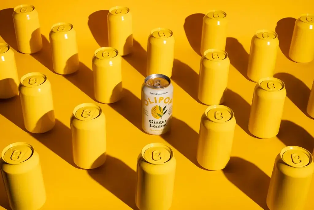 Olipop Ginger Lemon can among rows of yellow cans on a yellow background