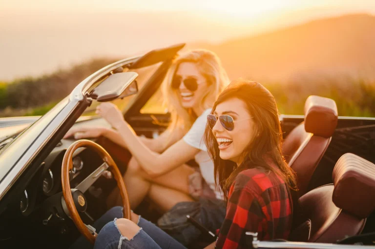 Two women in a convertible at sunset