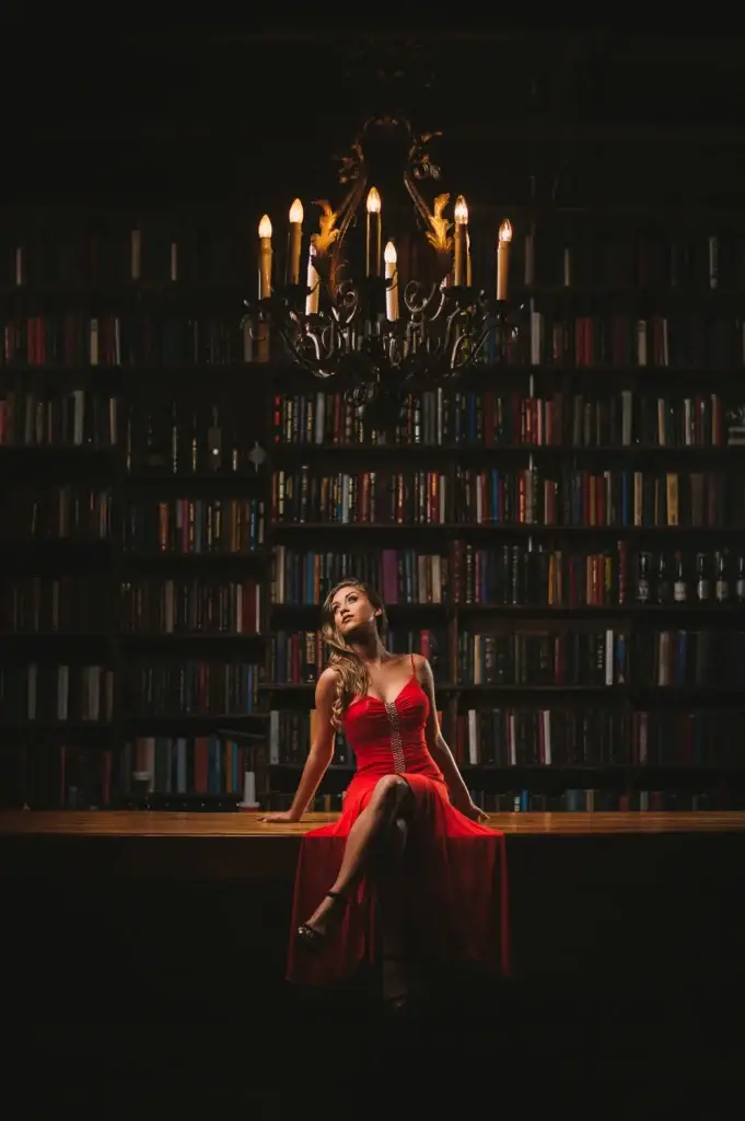 Woman in a red dress under a library chandelier