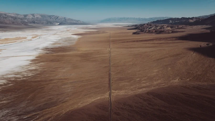 Aerial view of Badwater Road splitting glittering salt flats from the desert floor at Lake Manly, Death Valley